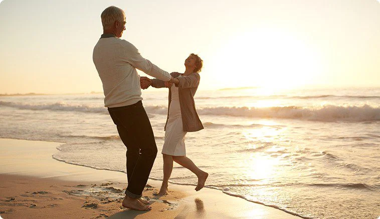 Father and daughter playing joyfully on the beach at sunset.